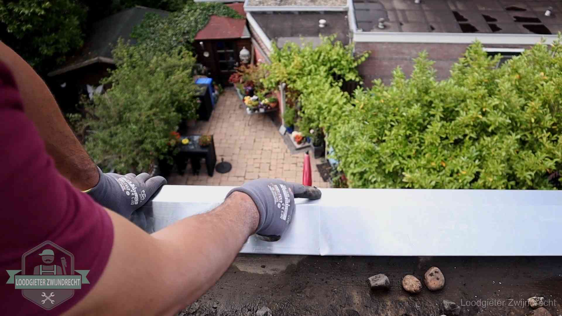 Vakman plaatst een daktrim op de dakrand van een woning in Zwijndrecht