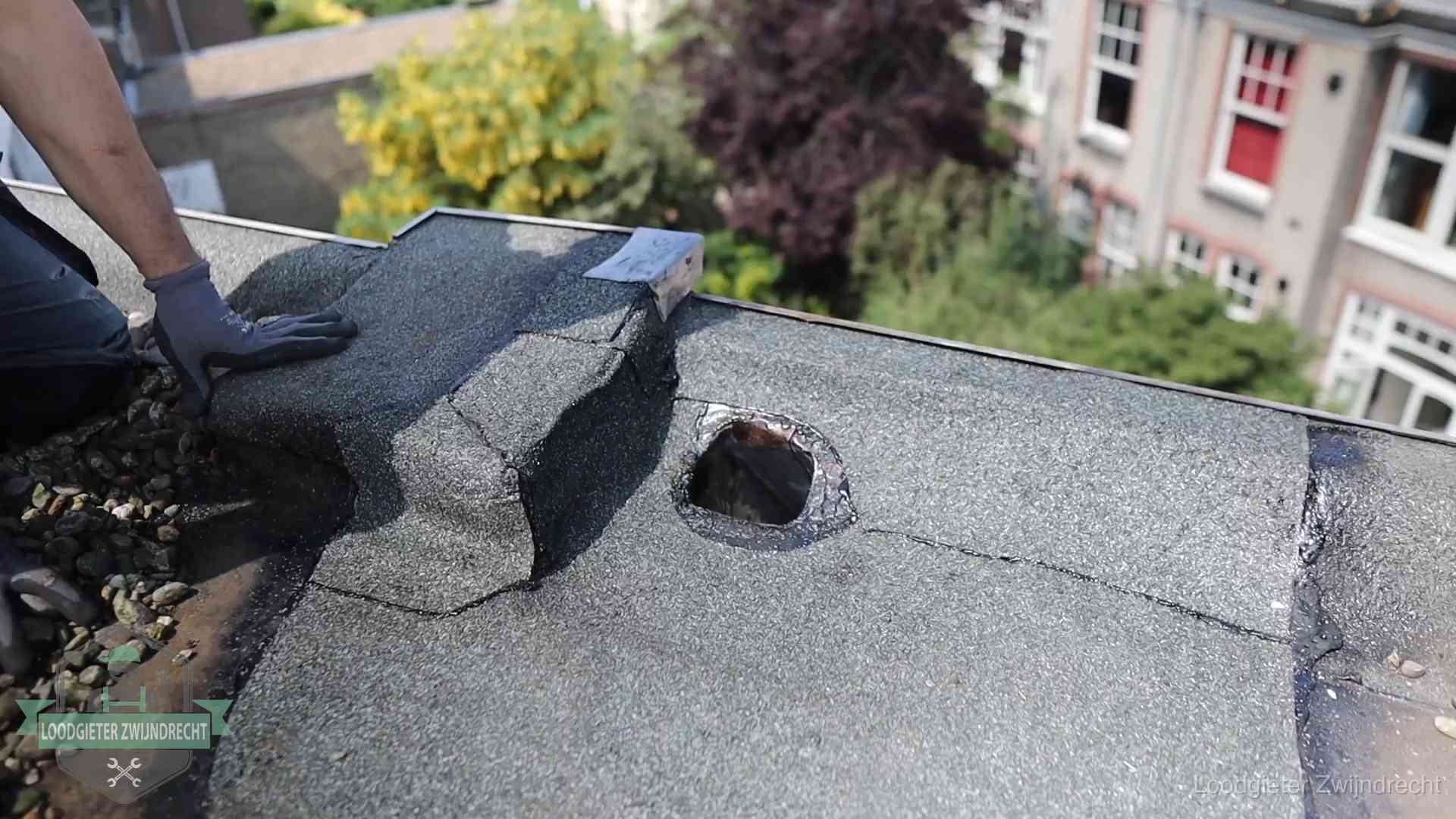 Loodgieter inspecteert een beschadigd bitumen plat dak tijdens een daklekkage-inspectie in Zwijndrecht