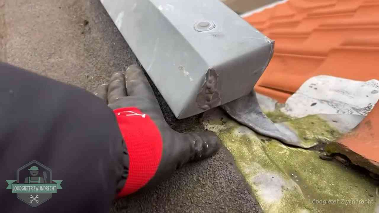 Controle van een zinken hemelwaterafvoer met loodslab bij dakpannen in Zwijndrecht