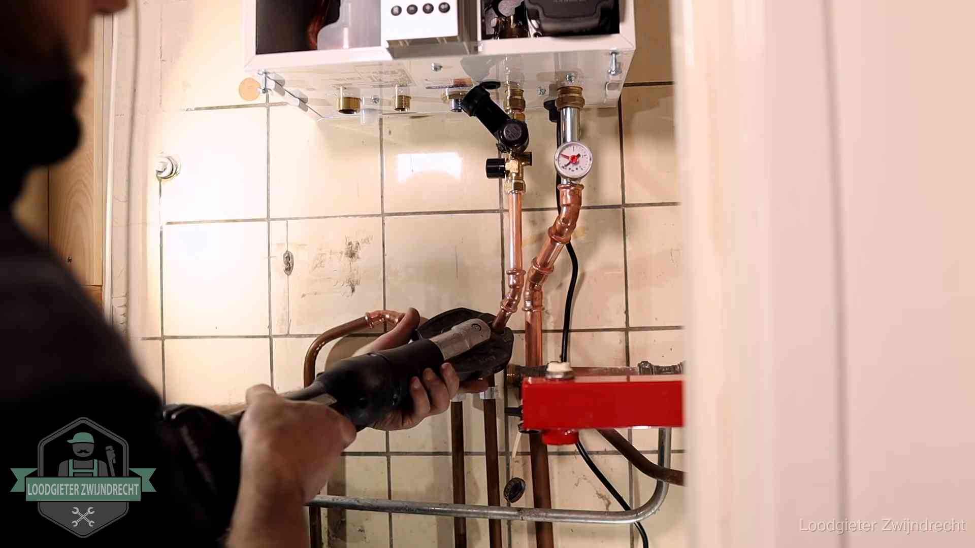 Monteur werkt aan de leidingen onder een cv-ketel in Zwijndrecht