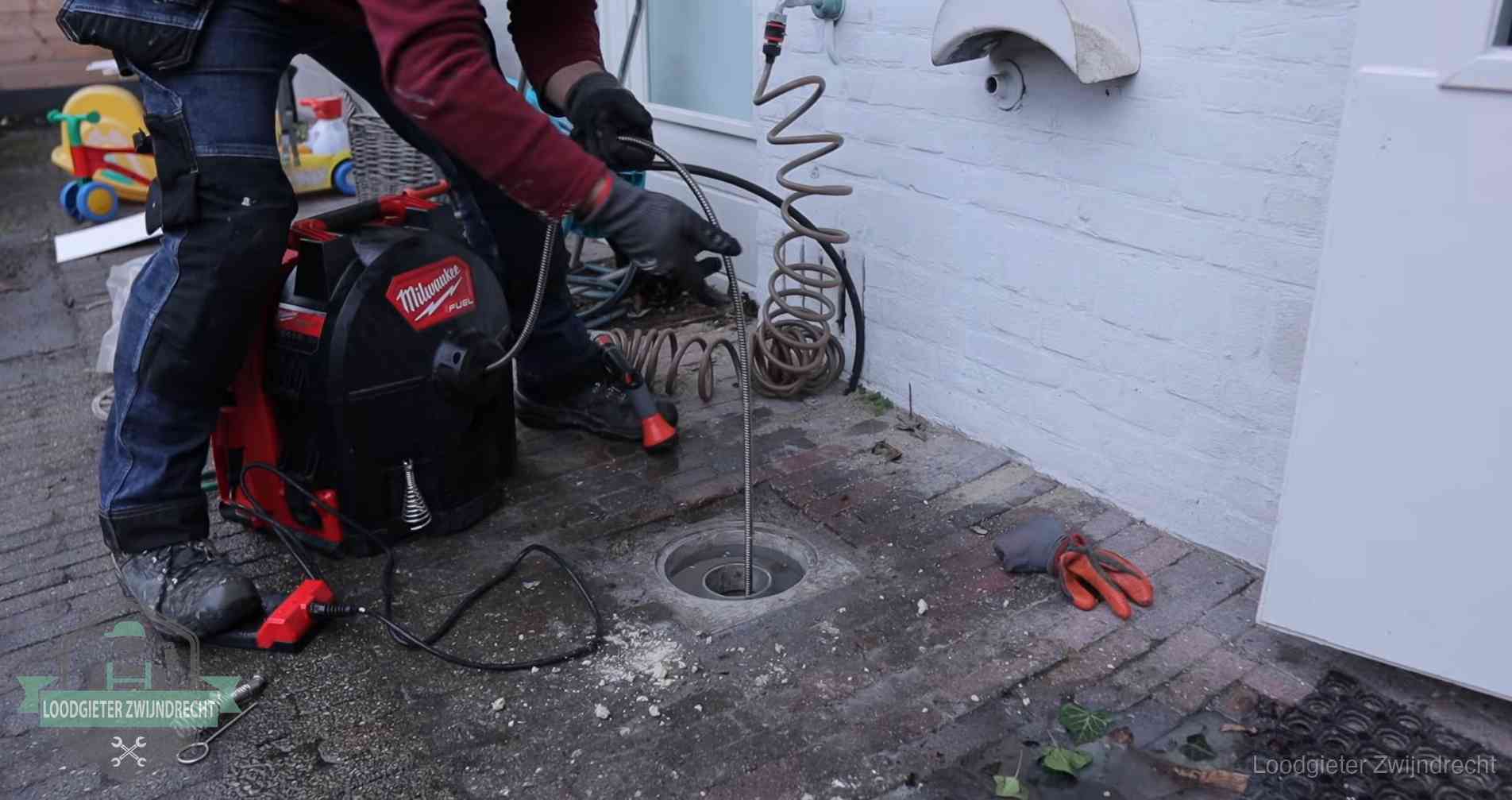 Erfgrens en gemeenteriool in Zwijndrecht Ontstoppingsputje in de bestrating naast de gevel van een woning in Zwijndrecht