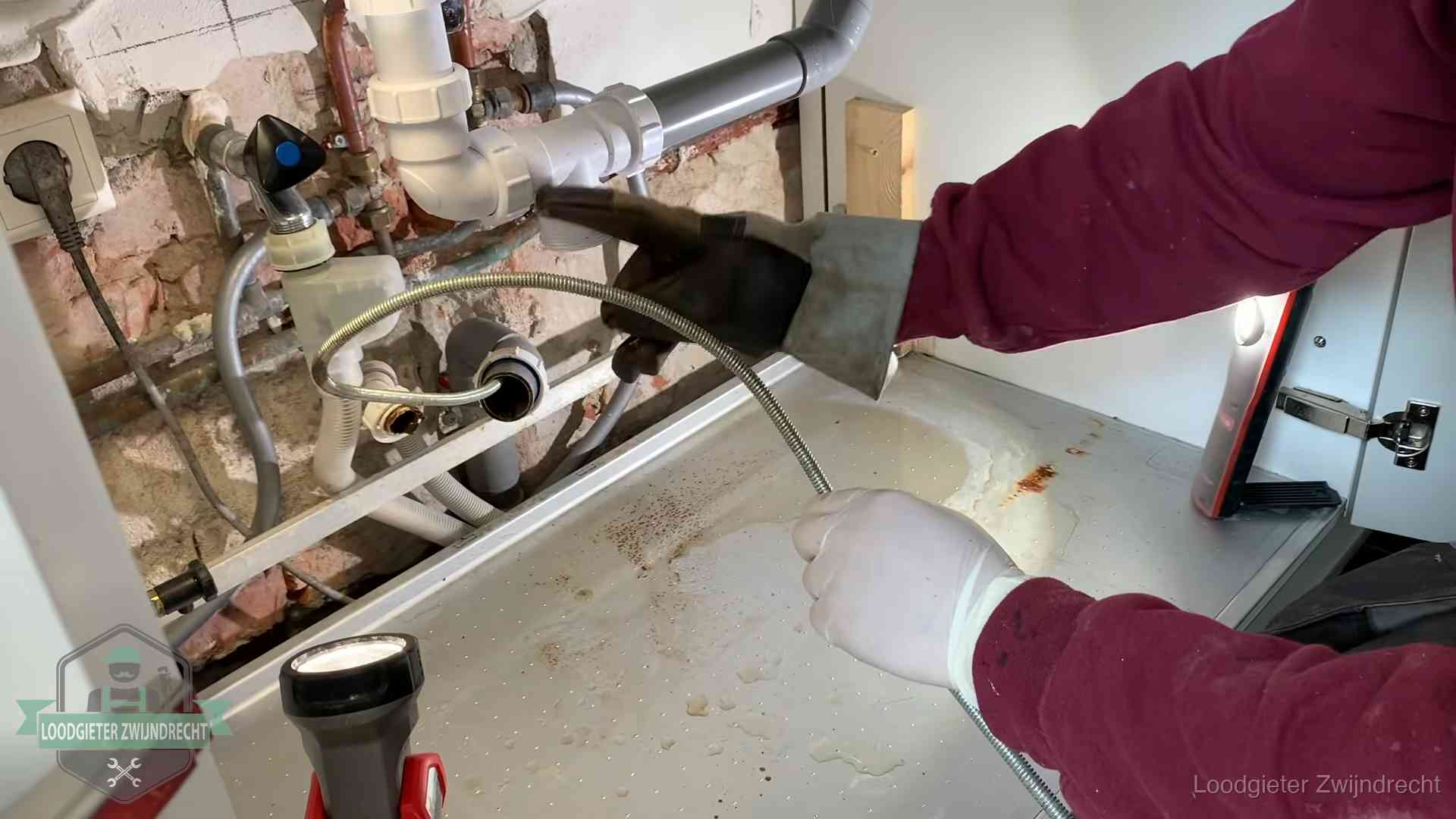Spiraal of hogedruk in Zwijndrecht Ontstoppingsveer gaat in een geopende sifonaansluiting onder het aanrecht in Zwijndrecht