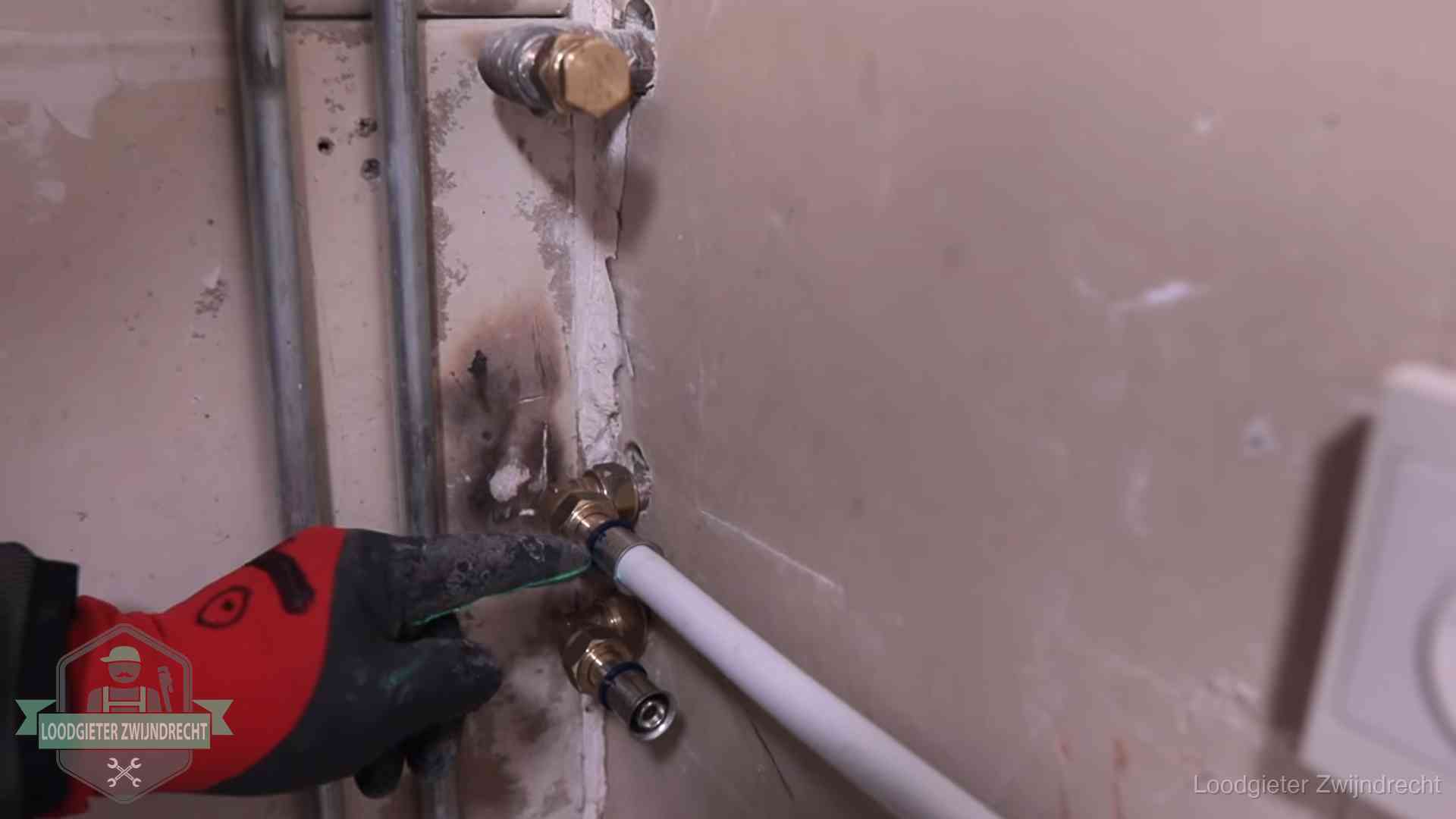 Loodgieter wijst de persfitting op nieuwe muuraansluitingen aan in een woning in Zwijndrecht