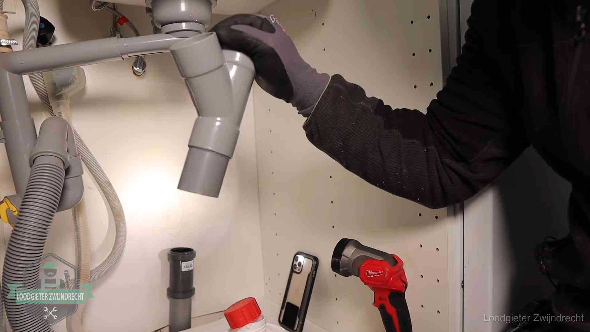Rioollucht in huis verhelpen in Zwijndrecht Loodgieter demonteert het sifon- en afvoerwerk onder een gootsteen in Zwijndrecht bij stankklachten