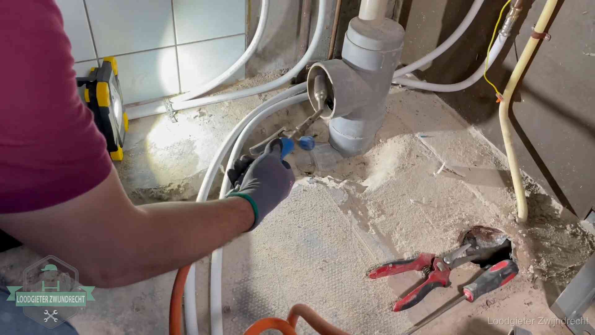 Loodgieter werkt aan leidingen bij een pvc-standleiding in een appartement in Zwijndrecht
