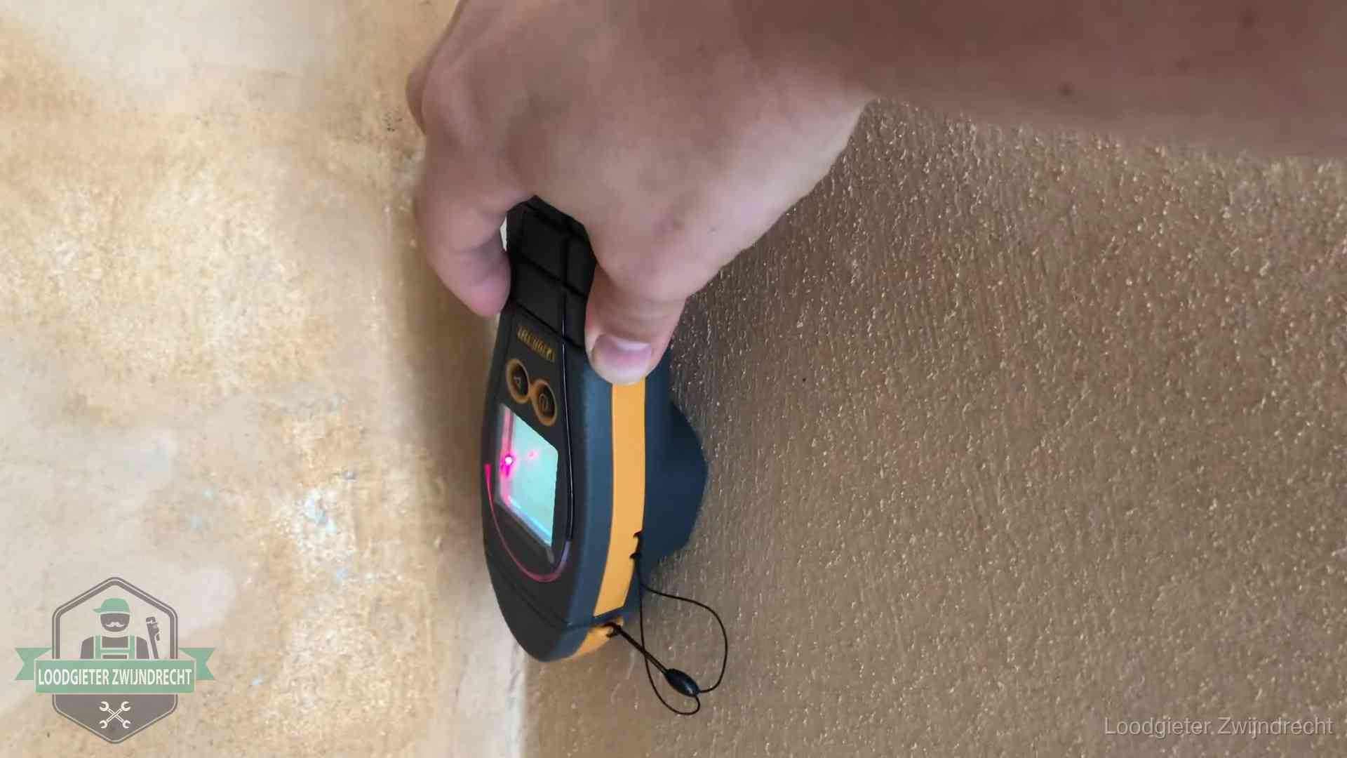 Vochtmeter tegen een muur met vochtplekken tijdens het opsporen van een daklekkage in Zwijndrecht