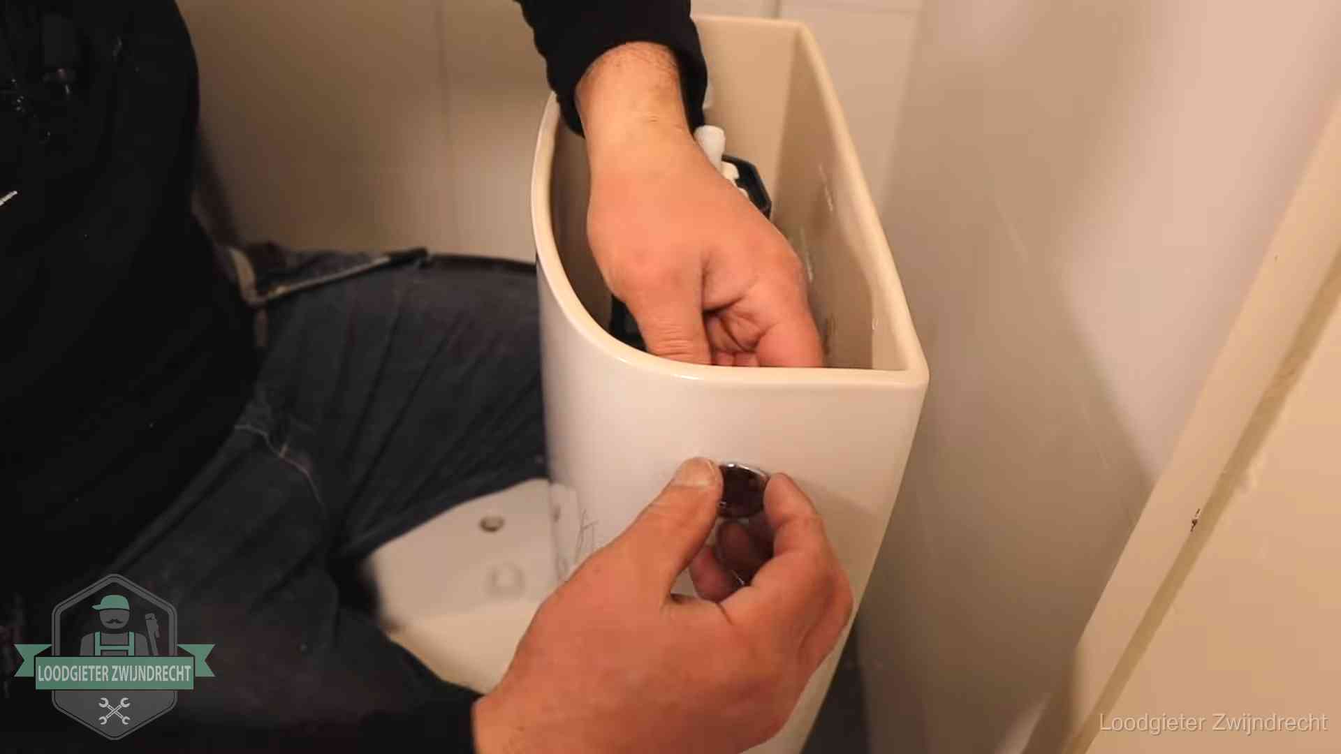 Je wc verstoppingsvrij houden in Zwijndrecht Drukknop van een duoblok-stortbak wordt gemonteerd bij een toilet in Zwijndrecht